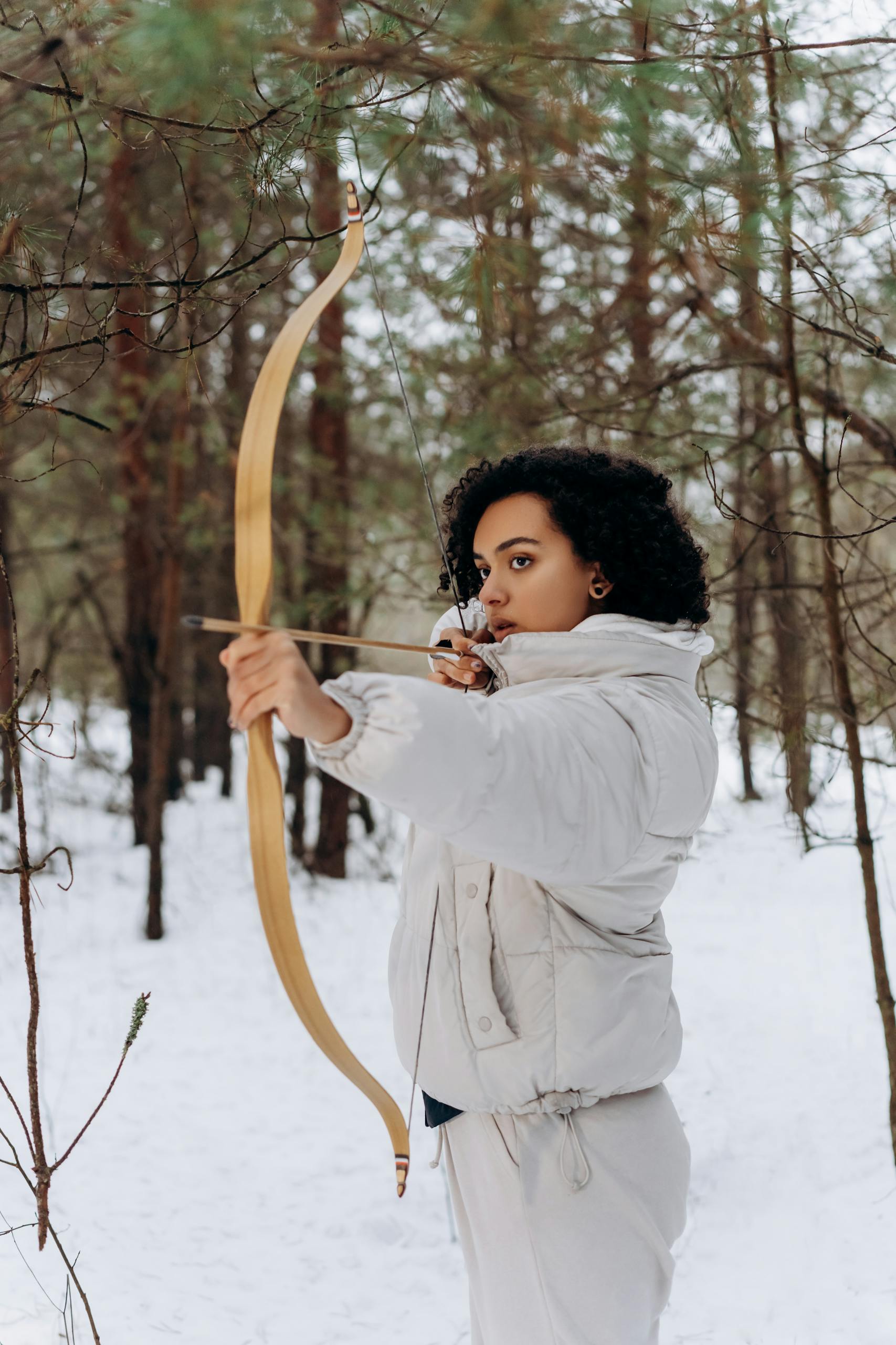 Woman in Gray Jacket Shooting a Bow and Arrow