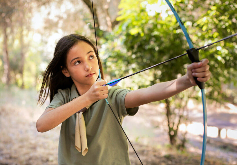 Girl archer with bow and arrow pulled back ready to shoot.